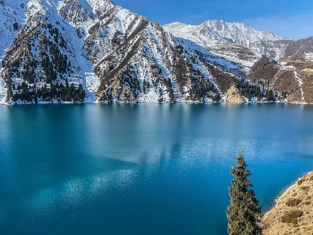 Schilderachtig uitzicht op het Grote Almaty-meer met sneeuwbedekte bergen op de achtergrond.