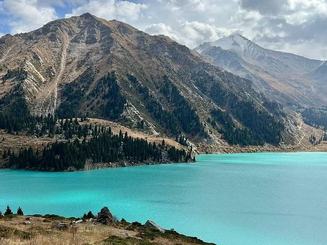 Wunderschönes türkisfarbenes Wasser des Großen Almaty-Sees, umgeben von Berggipfeln.