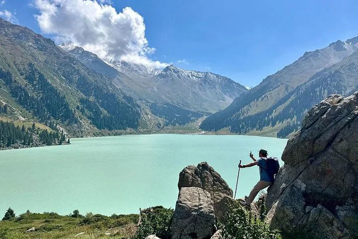 Persona in piedi su una roccia che scatta una foto al Lago Big Almaty.
