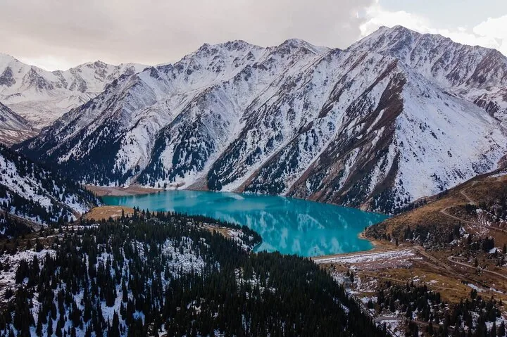 Vue aérienne montrant le Grand lac d'Almaty et les forêts de pins environnantes.